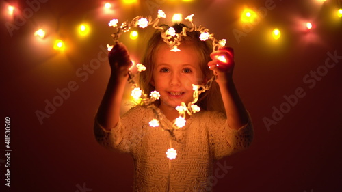 The girl holds in her hand a heart made of light bulbs and looks through it. Valentine's Day