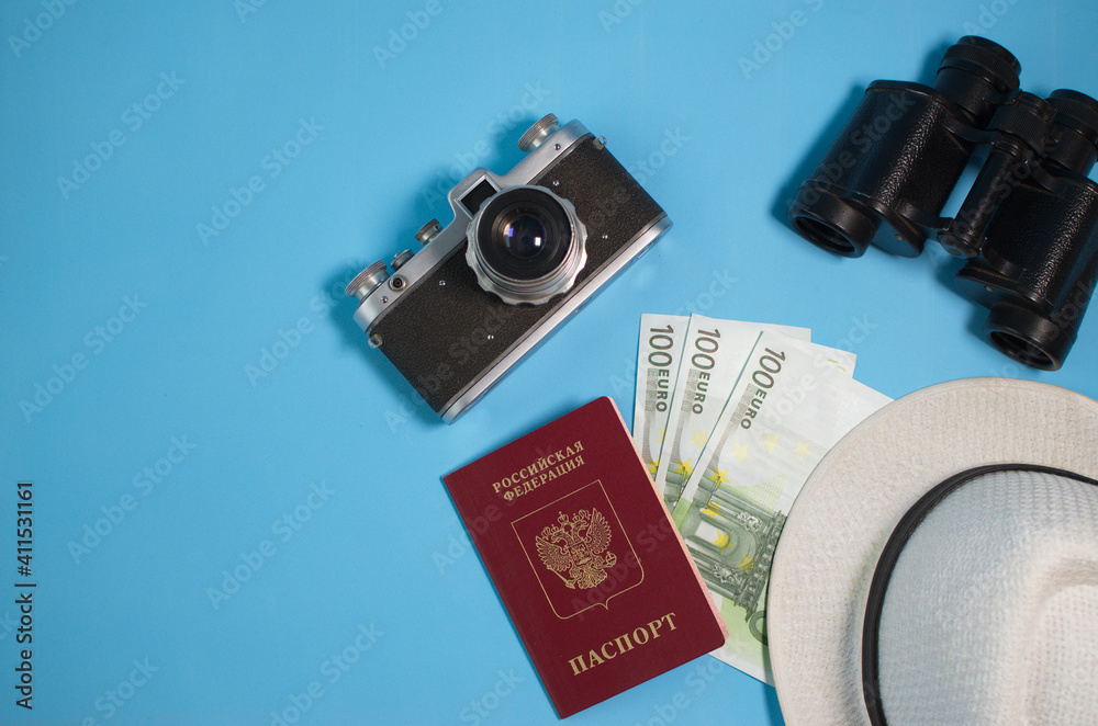 camera, binoculars, money, hat, passport lie on a blue background