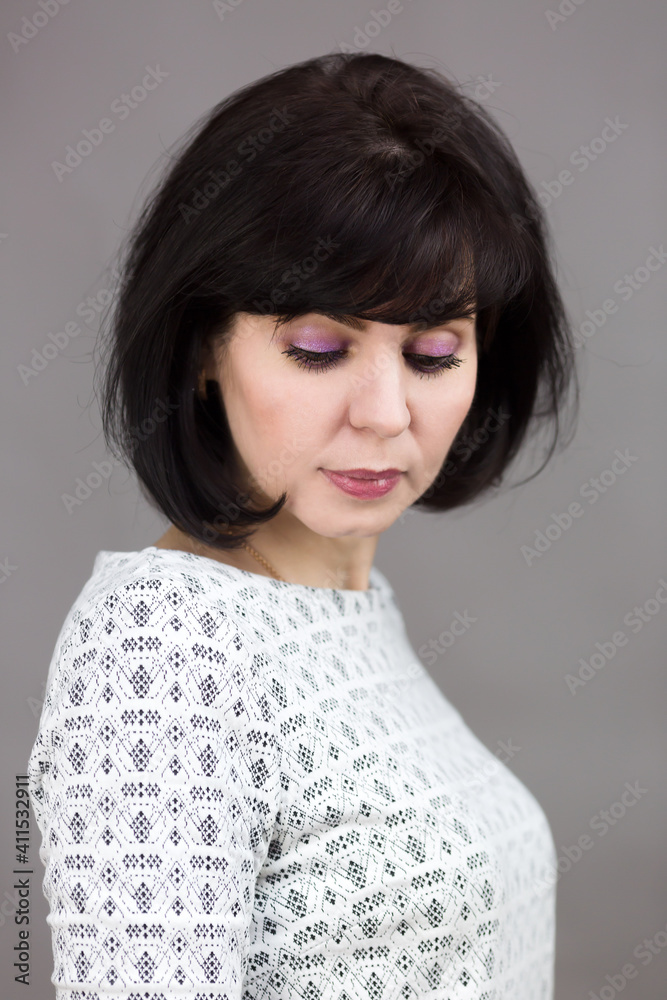 Brunette with downcast eyes on gray background. Brunette with downcast eyes on gray background.