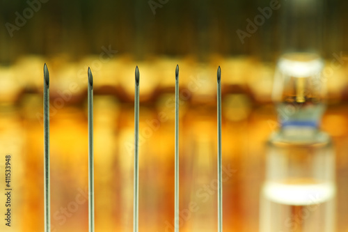  Tips of disposable needles for injection, blurred brown ampules background 