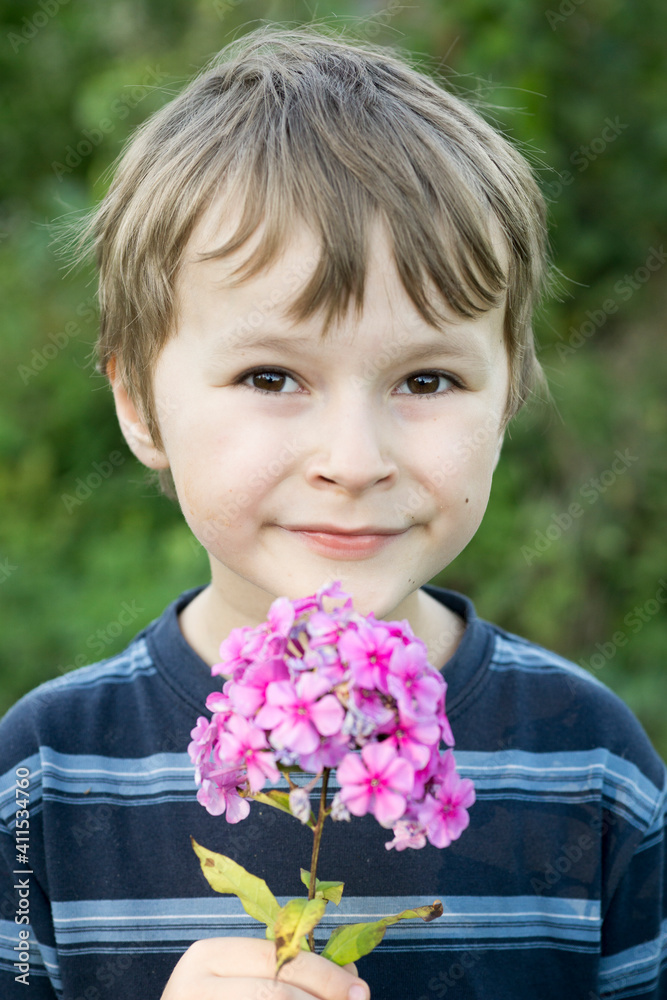 The boy is holding a pink flower. The boy is holding a pink flower.