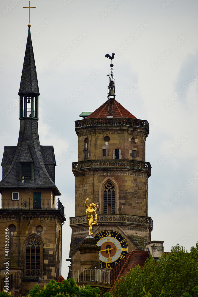 Photo with a Church, a clock tower and a Golden sculpture