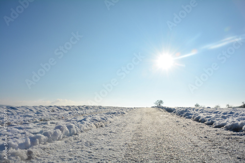 Snow-covered road in the country  with sun