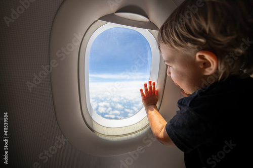cute toddler points his finger at the sky through the window. first flight concept, traveling with children.