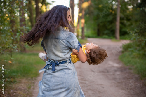 young woman plays with toddler girl in yellow in park