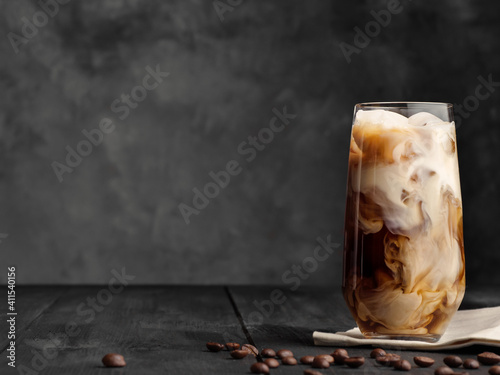 Iced coffee and milk in a highball glass on a gray background. Copy space. Space for text.