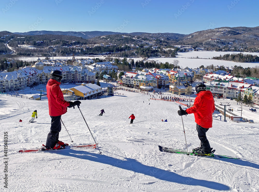 Obraz premium Skiers admiring Mont and Lake Tremblant village resort in winter, Quebec, Canada