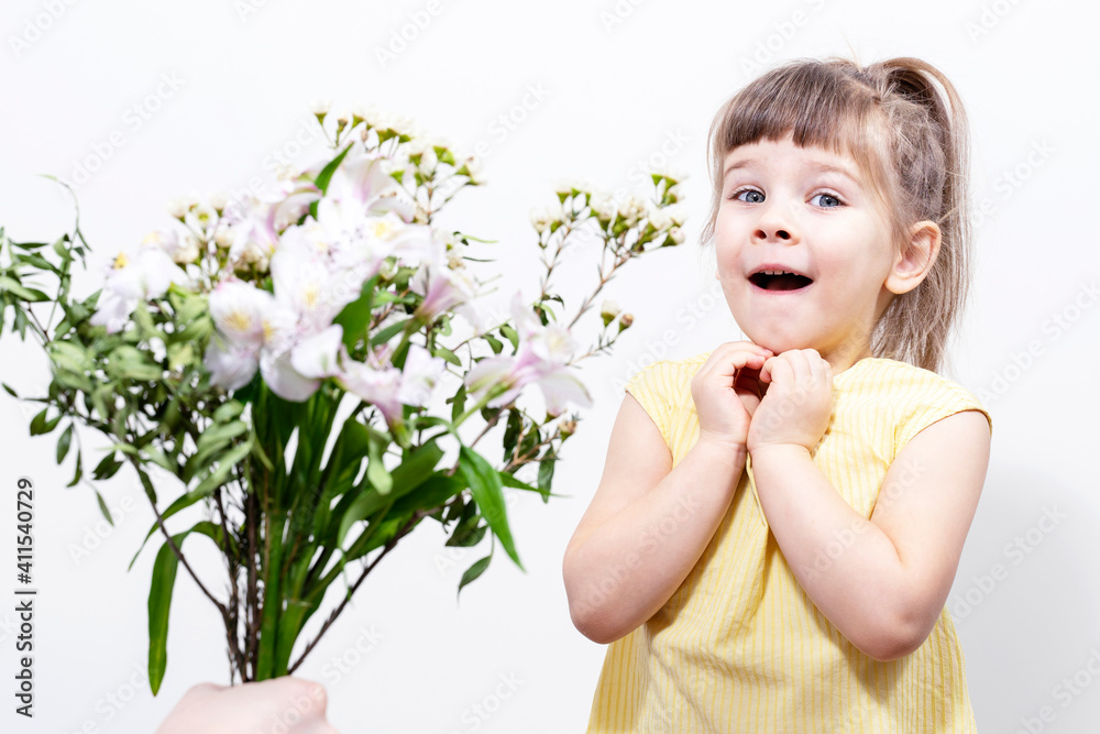 a man's hand holds out a bouquet of white flowers to a cute little girl in a yellow blouse. the child is delighted. 8 march concept a man's hand holds out a bouquet of white flowers to a cute little girl in a yellow blouse. the child is delighted. 8 march concept