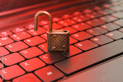 Open padlock on computer keyboard, red glow, symbol of hacked security