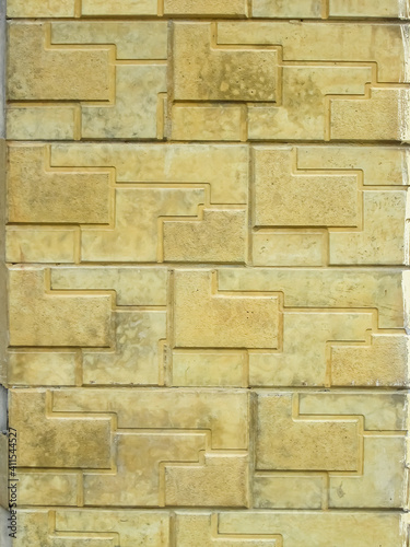 Yellow textured tiles on the cladding of the house. Vertical building background.