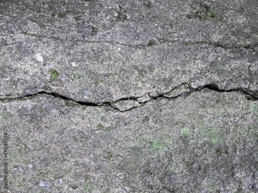 A crack in a concrete slab. Destroyed stone surface. House damage effect. A crack in a concrete slab. Destroyed stone surface. House damage effect.