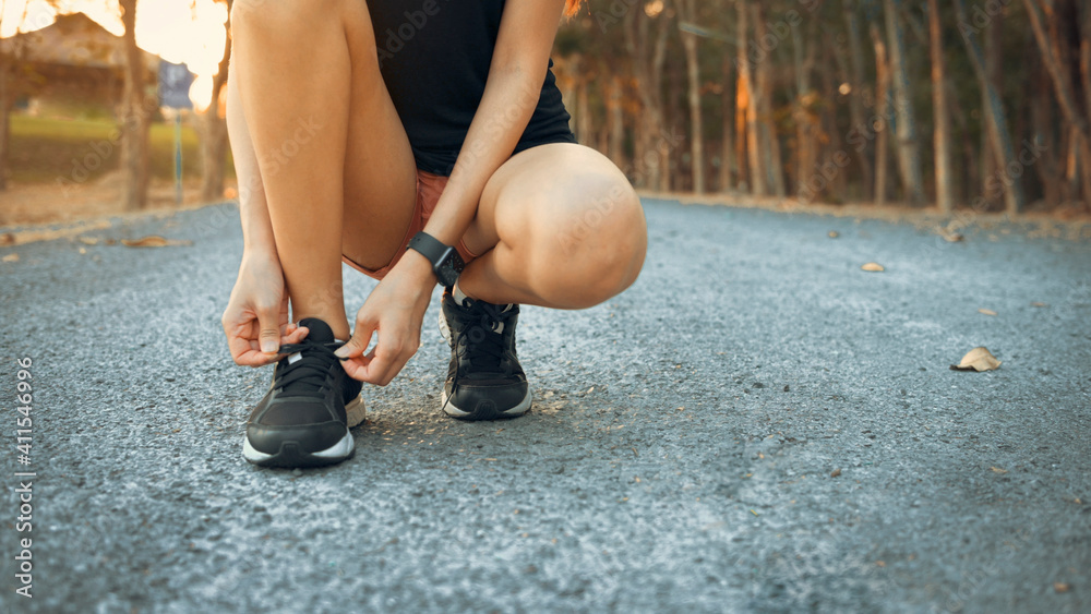 A young woman is doing Tie shoelaces before running in nature outdoor