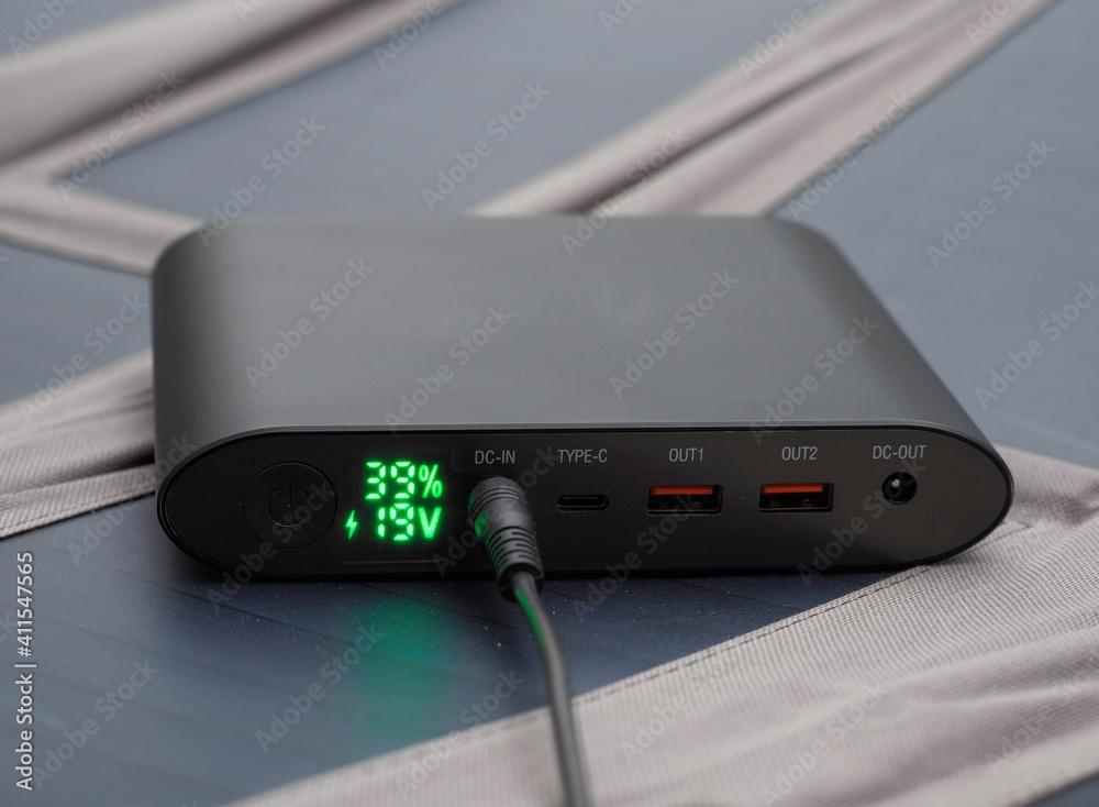Unabhängig - faltbares Solarpanel lädt Powerbank im Freien auf Unabhängig - faltbares Solarpanel lädt Powerbank im Freien auf