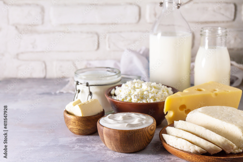 Various fresh dairy products, milk, sour cream, cottage cheese, yogurt and butter on a light stone countertop. Copy space.