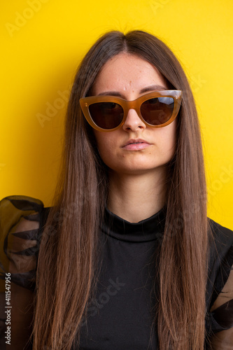 young woman with make-up in sunglasses and on yellow background