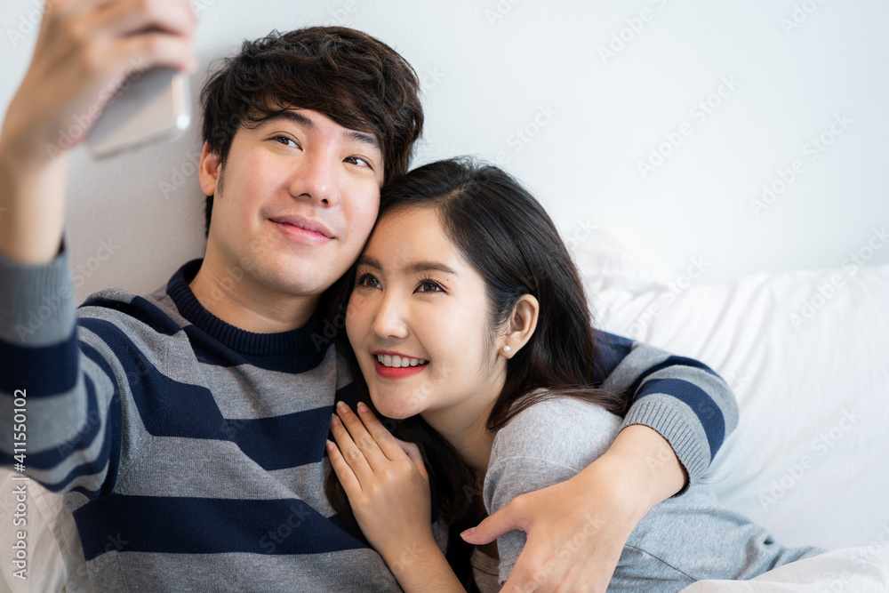 Asian young couples man and woman in bed room. A woman hugging boyfriend from behind, feeling love happiness with smiling Relationship of young woman and man remantic concept Asian young couples man and woman in bed room. A woman hugging boyfriend from behind, feeling love happiness with smiling Relationship of young woman and man remantic concept