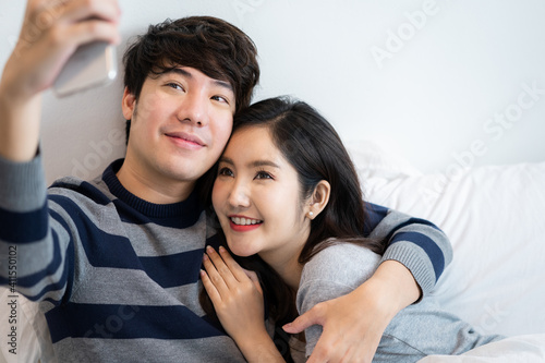 Asian young couples man and woman in bed room. A woman hugging boyfriend from behind, feeling love happiness with smiling Relationship of young woman and man remantic concept