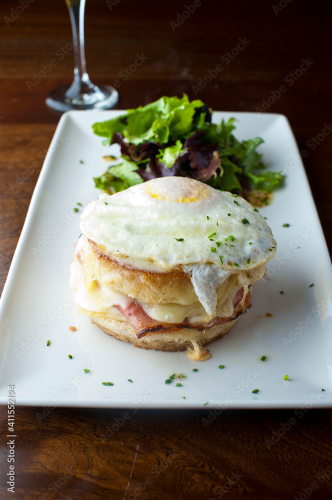 Croque madame or monsieur. Breakfast or brunch favorite: toast, with fried eggs, ham, cheese, and hollandaise sauce. Served with potato hash. Classic French bistro or American restaurant entree.