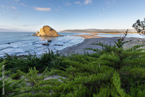 An idyllic and wild beach with a rocky island and a sand tongue splitting the sea from the river mouth and the forest trees. An amazing landscape threaten by human activity from Santiago city photo