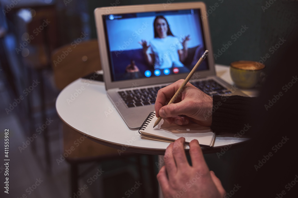 Man making notes during video conference indoors Man making notes during video conference indoors