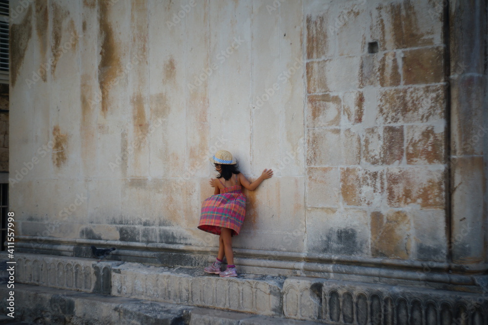 Girl balancing on an edge in the old town of Trogir