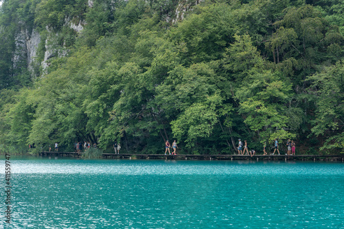 Plitvice, Croatia - Aug 11, 2020: Tourists walk by aqua color lake