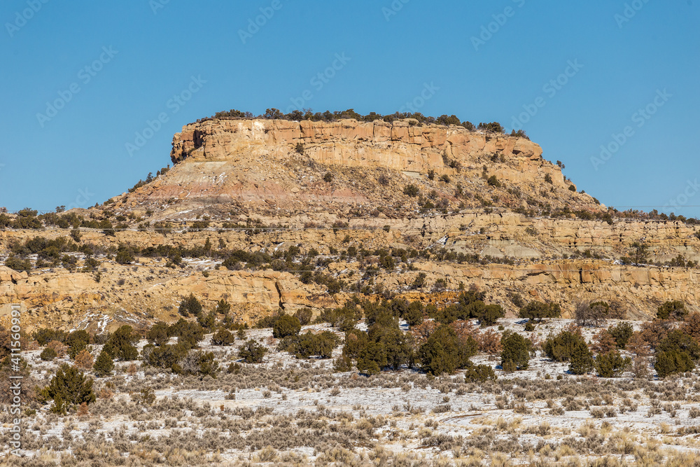 Closeup of tall rocky mesa plateau in snow covered desert on clear day in rural New Mexico