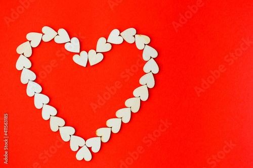 Heart lined with wooden hearts on a bright red background. Place for an inscription, romantic picture for Valentine's Day
