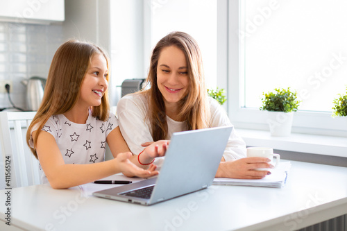 Smiling mom and daughter in front of a laptop monitor.