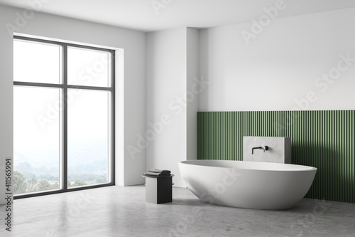 White and green bathroom with white bathtub, marble floor and window