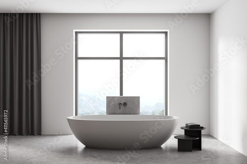 Wooden light bathroom with bathtub and towels near window