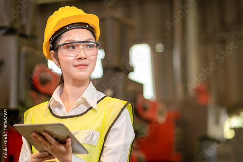 Happy confident Asian young engineer/business woman holding tablet in steel factory and looking at left side with copy space. © Sathaporn