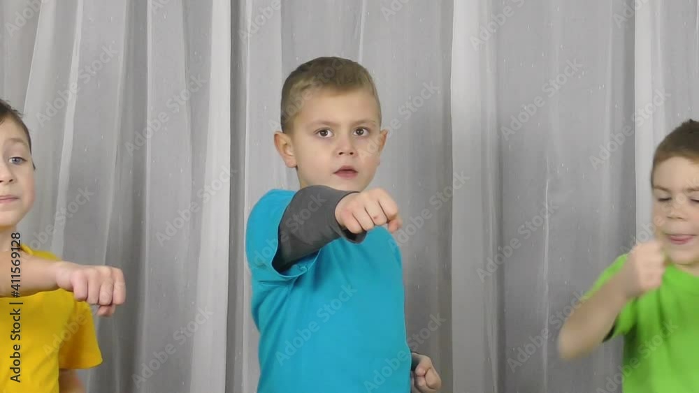 Little athletes in multi-colored T-shirts practice punches on a light background Little athletes in multi-colored T-shirts practice punches on a light background