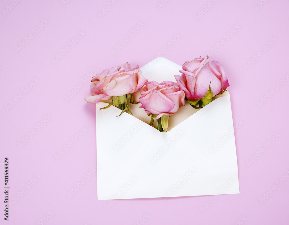 Top view flat lay white envelope with pink roses pink background Top view flat lay white envelope with pink roses pink background