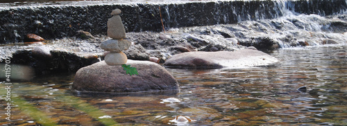 Pedras empilhadas com uma folha presa com gotas de água num pequeno rio de montanha - terapia ZEN photo