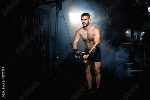 Brutal strong bodybuilder athletic man pumping up muscles workout bodybuilding muscular bodybuilder handsome men doing exercises in gym. atmosphere smoke