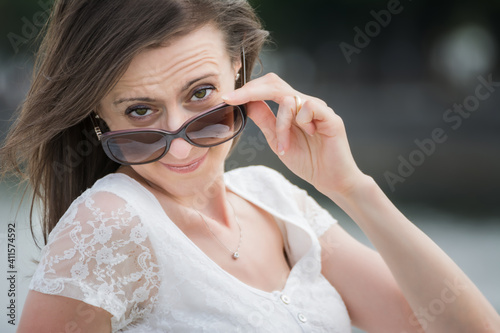 Portrait of young caucasian woman looking over big sunglasses