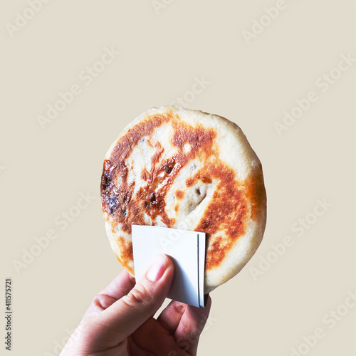 A hand holding Hotteok, sometimes called Hoeddeok, is a type of filled Korean pancake on isolated background. It is a snack from Korean Chinese cuisine and is a popular street food in South Korea. photo