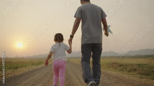 4k Video slow-motion, An Asian father took his daughter's hand for a walk. The right-hand holds a turbine During the sunset Family concept.
