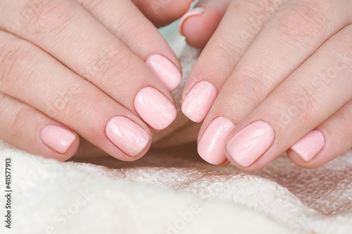 female hands with beautiful manicure and soft pink varnish on the nails..