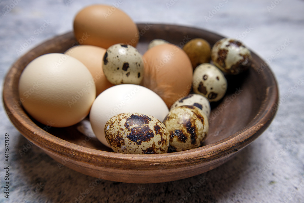 fresh quail and chicken eggs from the farm in a brown clay plate on a gray marble table. selective soft focus. High quality photo fresh quail and chicken eggs from the farm in a brown clay plate on a gray marble table. selective soft focus. High quality photo