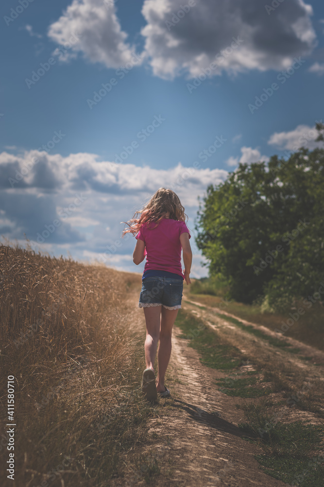 girl walking alone in magic summer afternoon in golden hour time