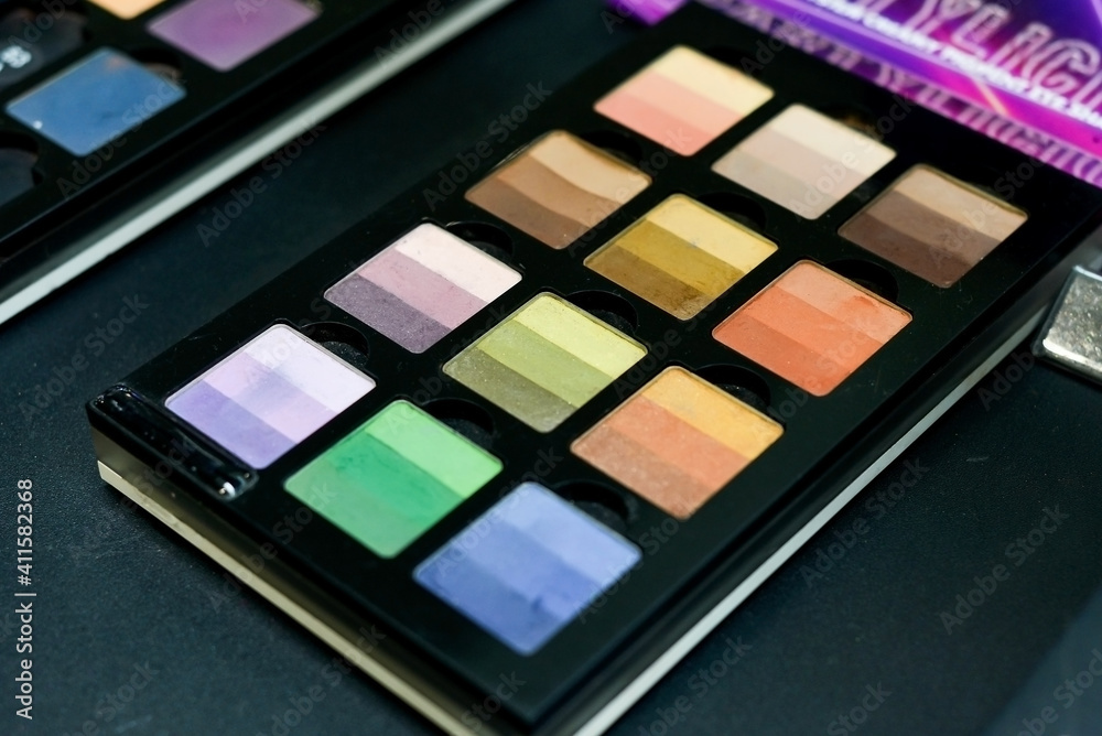 Many different female eyeshadows lie on the black table in the store. Many different female eyeshadows lie on the black table in the store.
