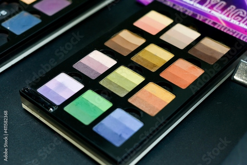 Many different female eyeshadows lie on the black table in the store.