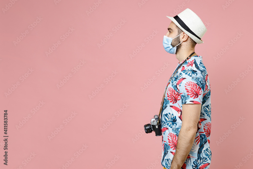 Side view of young traveler tourist man in face mask to safe from coronavirus virus covid-19 during quarantine isolated on pink background. Passenger traveling on weekend. Air flight journey concept. Side view of young traveler tourist man in face mask to safe from coronavirus virus covid-19 during quarantine isolated on pink background. Passenger traveling on weekend. Air flight journey concept.