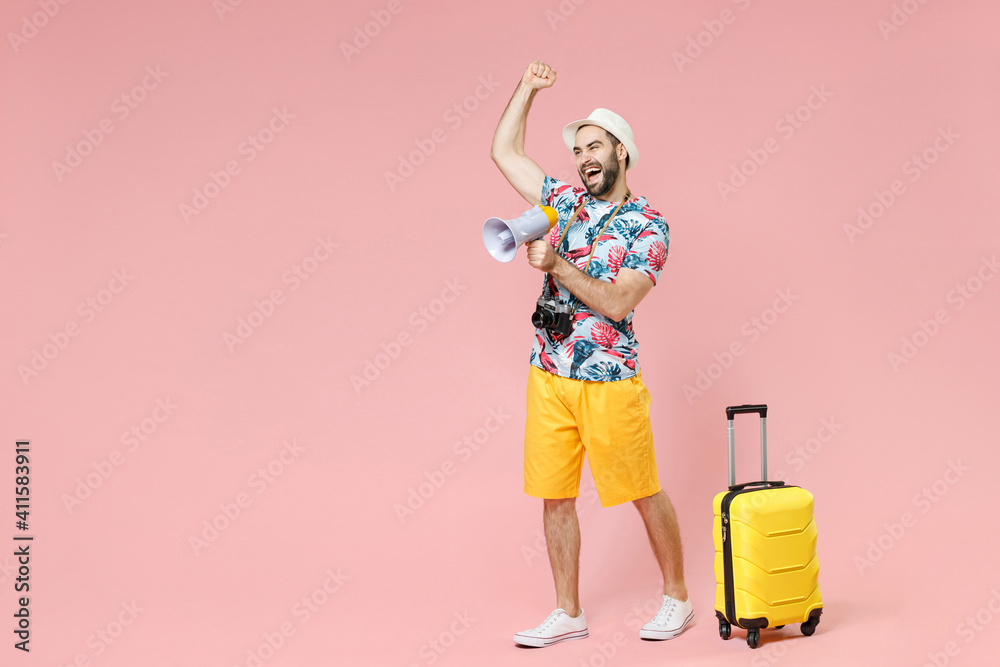 Full length of funny young traveler tourist man in summer clothes hat screaming in megaphone clenching fist isolated on pink background. Passenger traveling on weekends. Air flight journey concept. Full length of funny young traveler tourist man in summer clothes hat screaming in megaphone clenching fist isolated on pink background. Passenger traveling on weekends. Air flight journey concept.