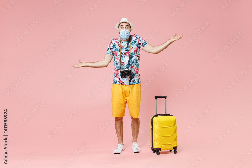 Full length of shocked traveler tourist man in sterile face mask to safe from coronavirus covid-19 spreading hands isolated on pink background. Passenger travel on weekend. Air flight journey concept. Full length of shocked traveler tourist man in sterile face mask to safe from coronavirus covid-19 spreading hands isolated on pink background. Passenger travel on weekend. Air flight journey concept.