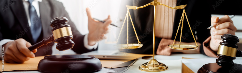Justice and law concept.Male judge in a courtroom with the gavel, working with, computer and docking keyboard, eyeglasses, on table in morning light Justice and law concept.Male judge in a courtroom with the gavel, working with, computer and docking keyboard, eyeglasses, on table in morning light