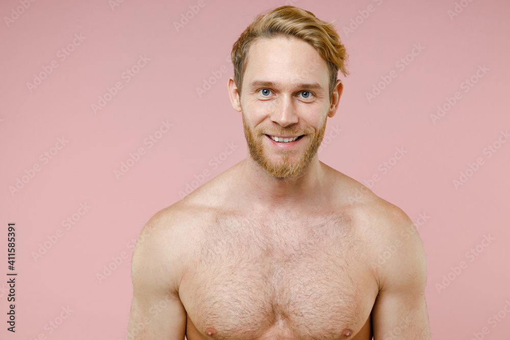 Fototapeta premium Smiling handsome bearded naked young man 20s years old perfect skin standing looking camera isolated on pastel pink color background studio portrait. Skin care healthcare cosmetic procedures concept.