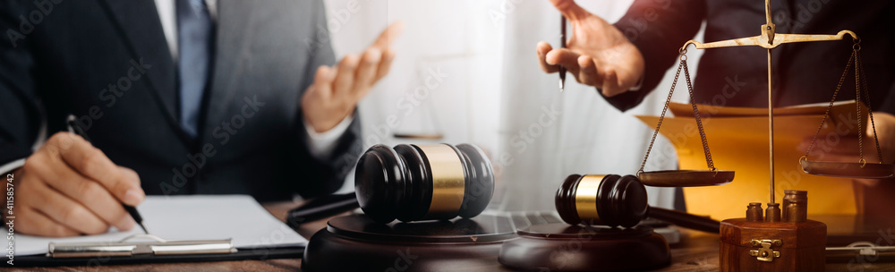 Justice and law concept.Male judge in a courtroom with the gavel, working with, computer and docking keyboard, eyeglasses, on table in morning light Justice and law concept.Male judge in a courtroom with the gavel, working with, computer and docking keyboard, eyeglasses, on table in morning light